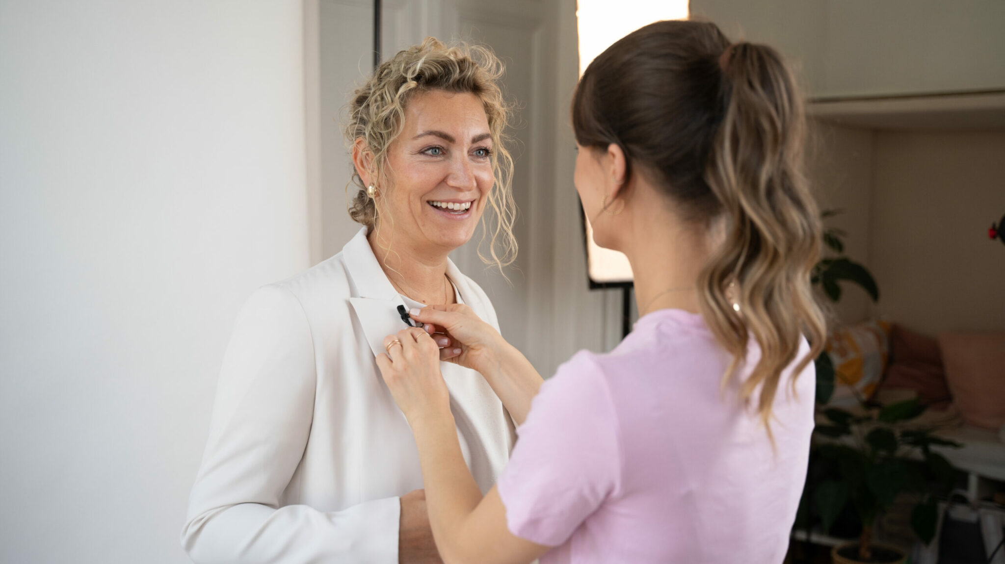 Julia montiert ein Mikrofon auf dem Blazer von Lisa Giessenwehrer.